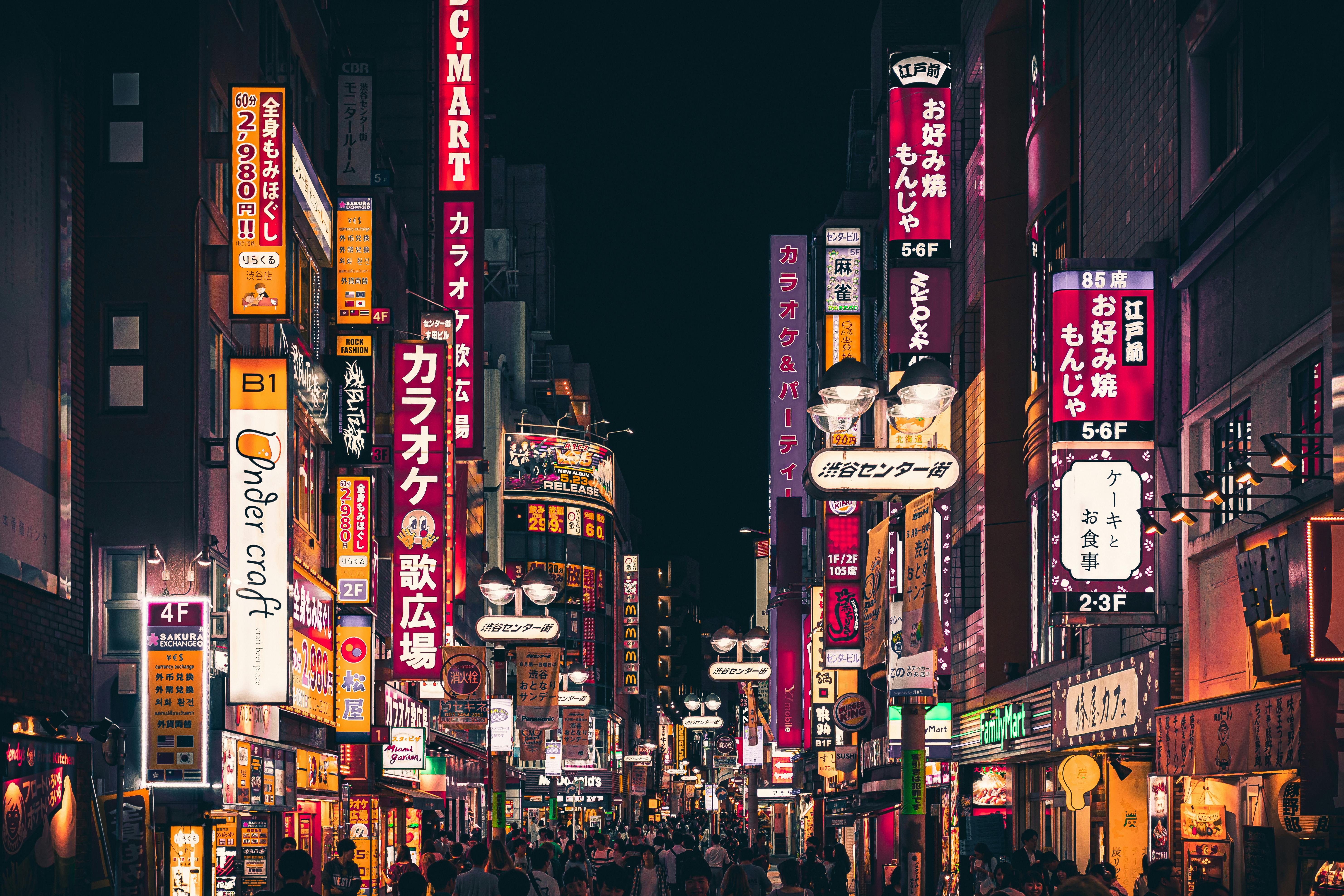 A vibrant city street in Tokyo at night with neon signs and people